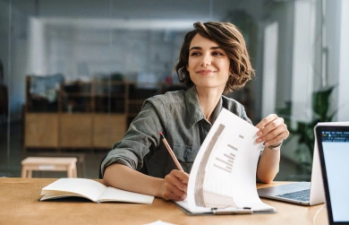 A young woman sitting at a desk, appearing thoughtful and focused on her work.