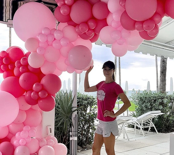 a woman standing next to an elaborate balloon arch on a bright, overcast day