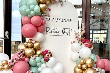 A large, white, semi-circular backdrop dominates the scene, adorned with the hotel's name and a "Happy Mother's Day" message in a stylish font.