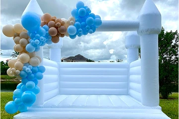 A white inflatable bounce house, shaped like a castle, sits outdoors.